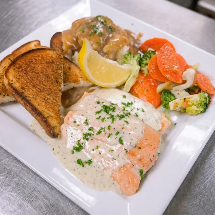 Baked salmon in creamy dill sauce with garlic toast, mashed potatoes and vegetables