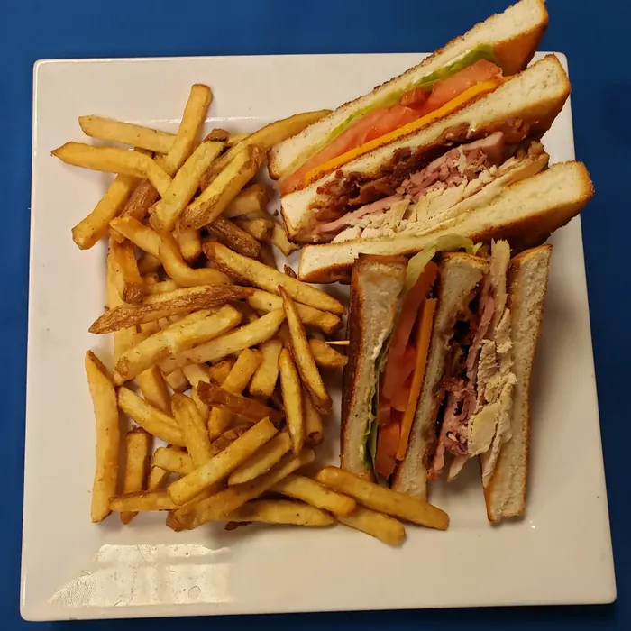 Clubhouse sandwich stacked with turkey, bacon and tomato, served with fries