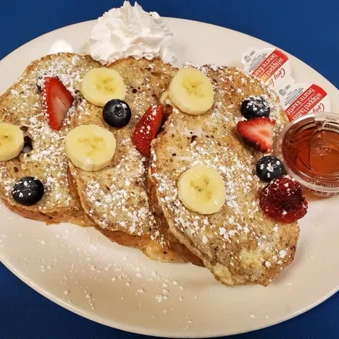 French toast dusted with icing sugar and topped with fresh berries and banana