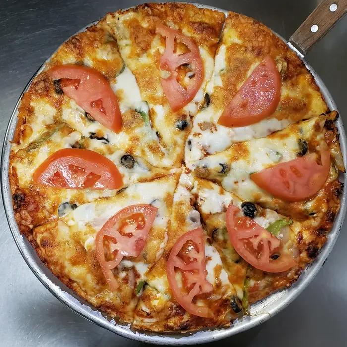Greek vegetarian pizza topped with fresh tomato, olives and melted cheese