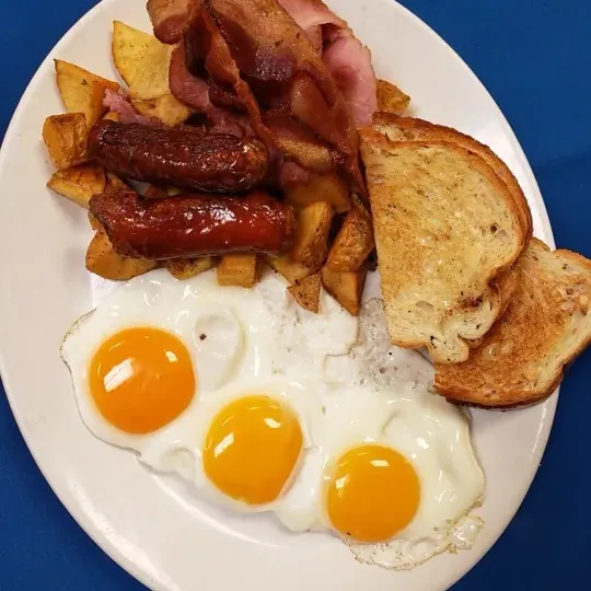 Harvest Breakfast with three eggs, bacon, ham, sausage, potatoes and toast