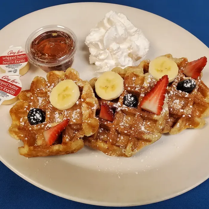 Homemade waffles with strawberries, blueberries, banana and whipped cream