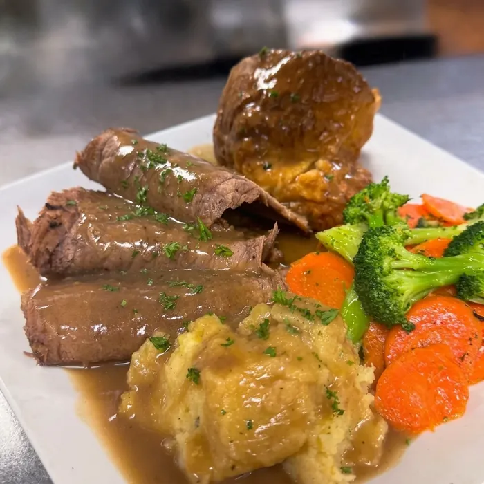 Roast beef dinner with Yorkshire pudding, mashed potatoes, gravy and seasonal vegetables