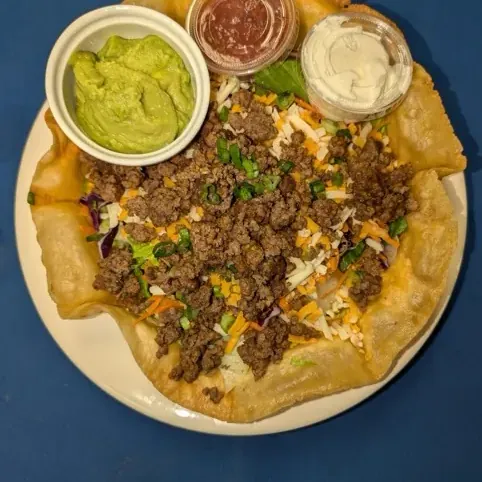 Taco salad in a crisp tortilla bowl with seasoned beef, guacamole and salsa